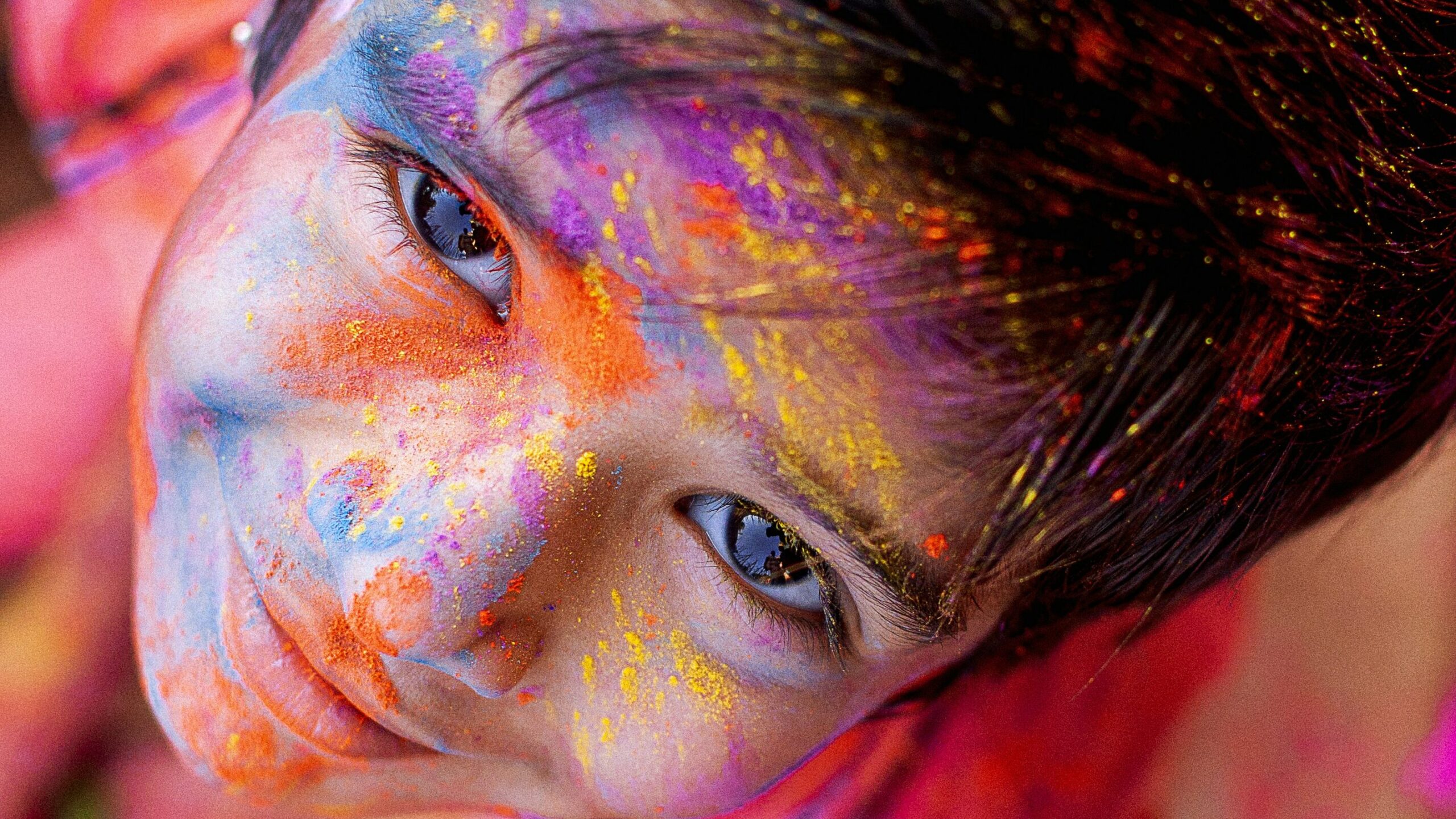 Child looking up with face covered in Waterless Holi dry Colours: advocating Eco-friendly Practices.
